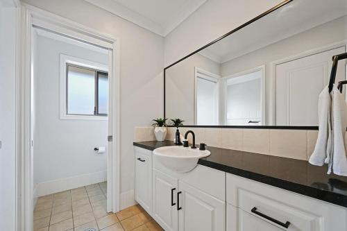 uma casa de banho branca com um lavatório e um espelho em McIntosh - Grand Family Home, Elegant Entertainer em Orange