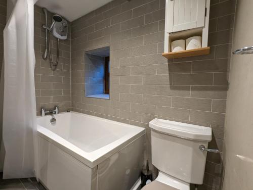 a bathroom with a tub and a toilet and a sink at Stoneswood Cottage & Garden, Delph, Saddleworth in Delph