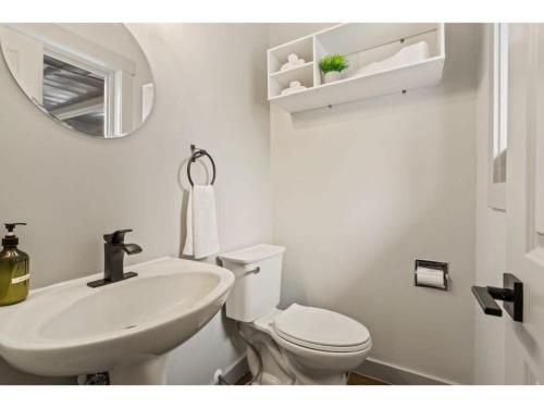 a white bathroom with a toilet and a sink at Evergreen Escape I Fireplace I Walk to the Lake in Invermere