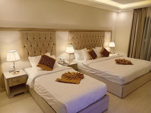 a hotel room with two beds and two lamps at Petra Premium Hotel in Wadi Musa