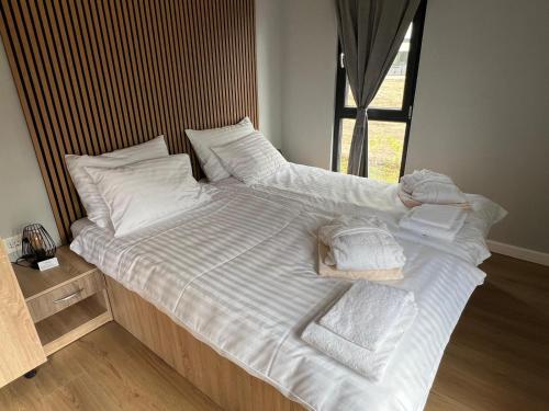 Una cama grande con sábanas blancas y toallas. en Review Resort&Spa, en Vadu Crişului