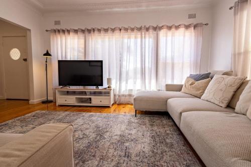 a living room with a couch and a flat screen tv at Crown Comforts - Family Escape, Firepit in Dubbo