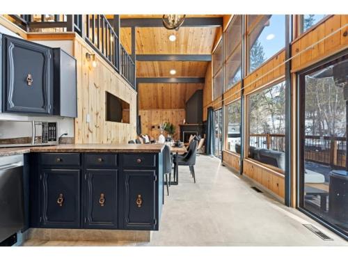 a kitchen with black cabinets and a dining room at The Matterhorn I HotTub I Ping Pong I Chalk Wall in Fairmont Hot Springs
