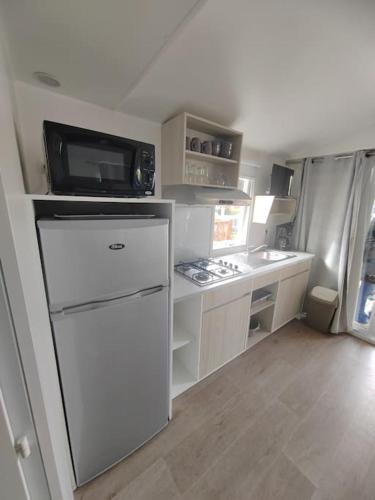 une petite cuisine avec un réfrigérateur et un micro-ondes dans l'établissement Mobilhome Confort en camping 4*, au Grau-du-Roi