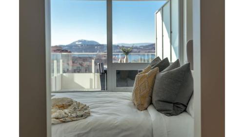 a bed in a room with a large window at The Luna l No Service Fees l Pool l HotTub in Kelowna