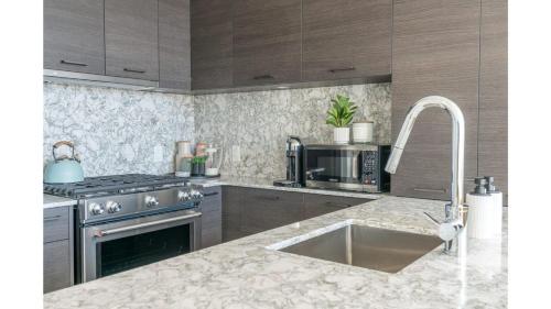 a kitchen with a sink and a stove top oven at The Luna l No Service Fees l Pool l HotTub in Kelowna
