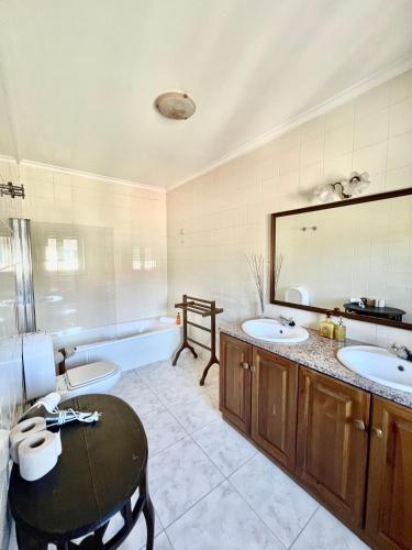 a bathroom with two sinks and a tub and a table at Quinta do Casarão by VinteOito - Casa de Campo com Piscina in Amarante