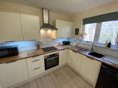 uma cozinha com armários brancos, um lavatório e uma janela em Treetops - Bright 2 Bed Flat - Super Location em Inverness