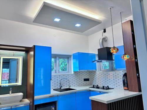 a blue kitchen with a sink and blue cabinets at Nishwas Homes in Ernakulam