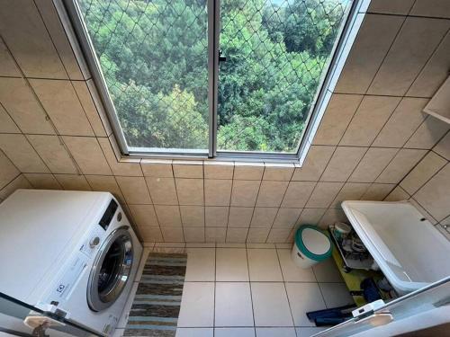 a washing machine in a small bathroom with a window at AP Condomínio Fechado in São José dos Pinhais