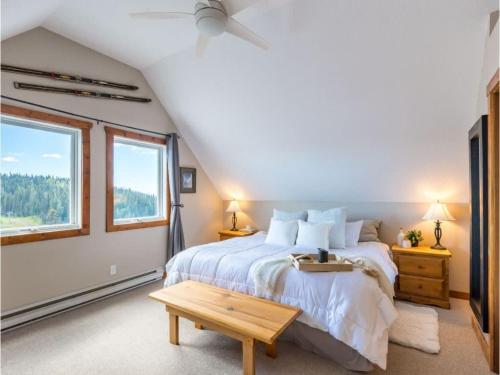 a bedroom with a bed and a table and windows at The Alpine I No Service Fee's I Ski-in Ski-Out I in Silver Star