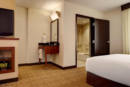 a hotel room with a bed and a television and a bathroom at Hyatt Place Coconut Point in Estero