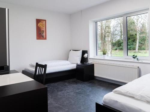 a bedroom with two beds and a desk and a window at Gästehaus Moorblick in Osten