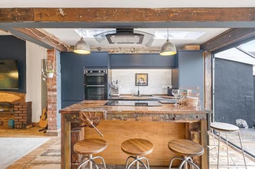 a kitchen with blue walls and a counter with stools at Stylish House w Free Parking Nr Exeter Centre in Exeter
