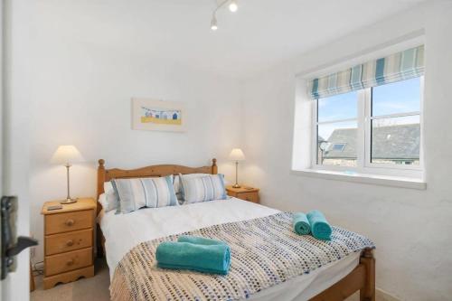 a bedroom with a bed with two towels on it at Cosy Cottage Huge Garden w Lake BBQs & Seating in Slapton
