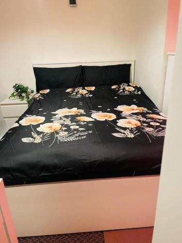 Una cama con un edredón negro con flores. en Luxury Top Quality natural Bedroom Near the Train Station, en Barking