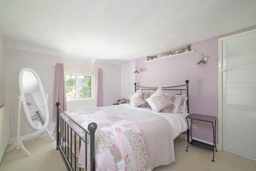 - une chambre rose et blanche avec un lit et un miroir dans l'établissement Idyllic Cottage in Dorset Garden & Parking, à Gillingham