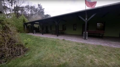 un edificio verde con mesas de picnic y una bandera en AGROTURYSTYKA WIOSNA en Wiosna