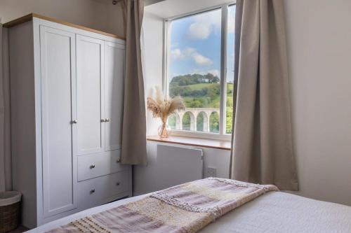 1 dormitorio con cama y ventana grande en Charming Cottage with Stunning Views, en Calstock