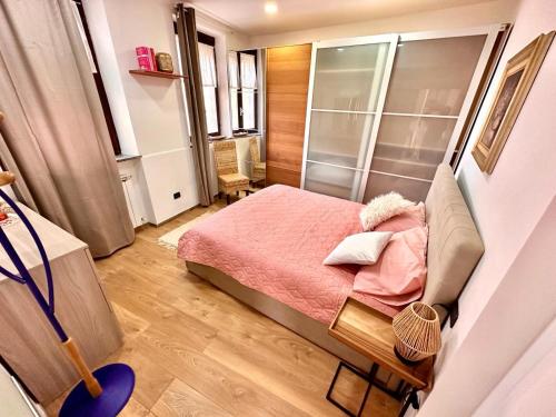 Un pequeño dormitorio con una cama rosa en una habitación en Casa Emma, en Porto Ceresio