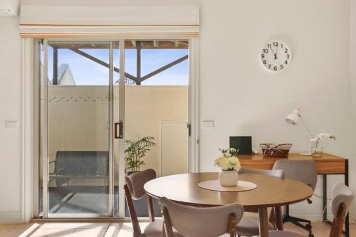 a dining room with a table and chairs and a clock at Little Malop Escape I Central Geelong in Geelong