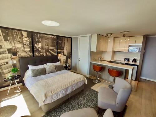 a bedroom with a bed and a chair and a kitchen at Apartamento Avenida Kennedy in Santiago
