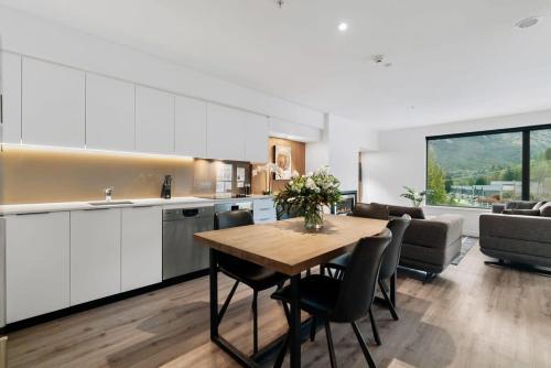 a kitchen and living room with a table and a couch at Te Awa at La Residence du Parc in Queenstown