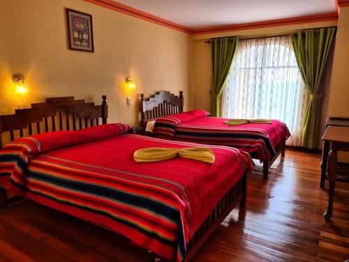 1 dormitorio con 2 camas con sábanas rojas y arcos amarillos en HOTEL MIRADOR AL TITICACA, en Copacabana