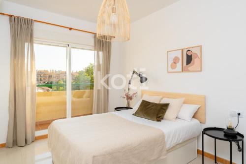 um quarto branco com uma cama e uma grande janela em Koti Rentals - Nenúfar em Fuengirola