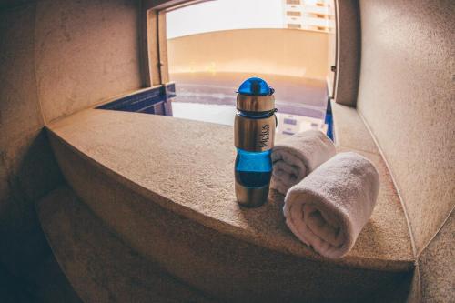a blue and gold thermos in a bathroom with towels at Cullinan Hplus Premium Flat Vip in Brasilia