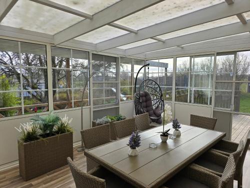 einen Wintergarten mit einem Tisch, Stühlen und Fenstern in der Unterkunft hus,2 sovrum, 2 våning, 2 badrum in Simrishamn