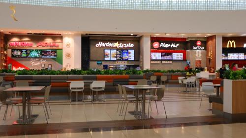 a restaurant with tables and chairs in a mall at ZenDen 1BR -Serene Zen-Inspired Stay in Oasis Masdar, Near Masdar Park in Abu Dhabi