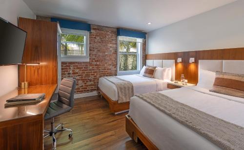 a hotel room with two beds and a desk and a television at Riviera Beach House in Santa Barbara