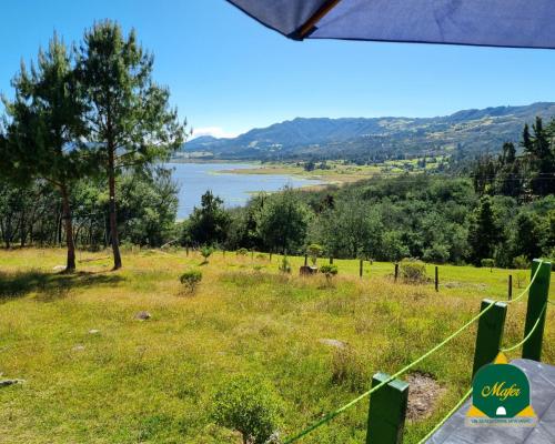 a view of a field with a lake in the background at Glamping Mafer 4 Tipi pequeño in Guatavita