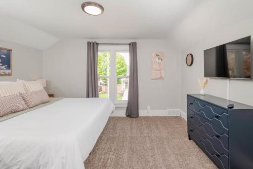 ein weißes Schlafzimmer mit einem großen Bett und einem TV in der Unterkunft Bowen Street Bungalow - 3 bed 2 bath in Oshkosh