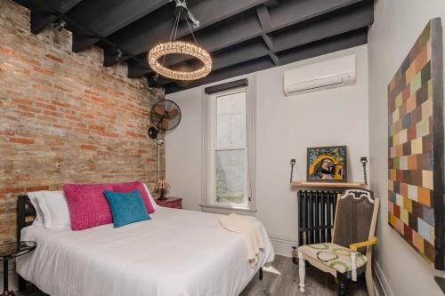 um quarto com uma cama branca e uma parede de tijolos em ᴘɪɴʙᴀʟʟ ᴘᴇɴᴛʜᴏᴜꜱᴇ em Appleton