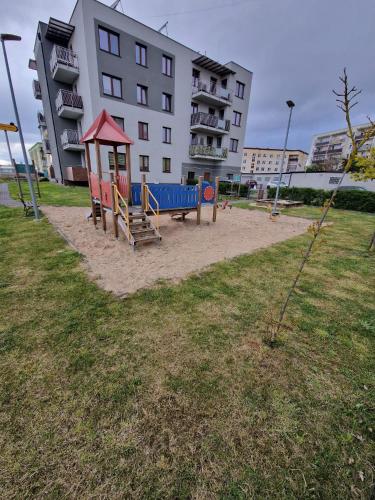 a playground in a park in front of a building at Apartament Pisz in Pisz