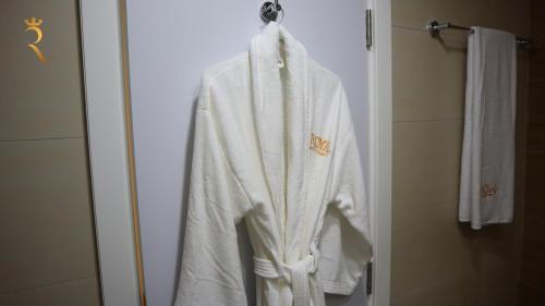 a white robe hanging on a door in a bathroom at Urban Oasis Retreat Transit - 2BR duplex in Abu Dhabi