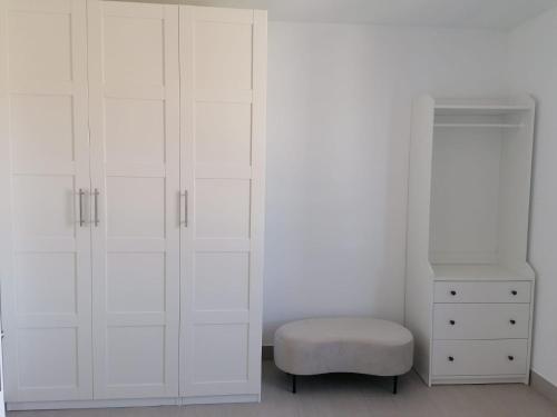 a white bedroom with white cabinets and a stool at O lar da Tia Carmen in Neaño
