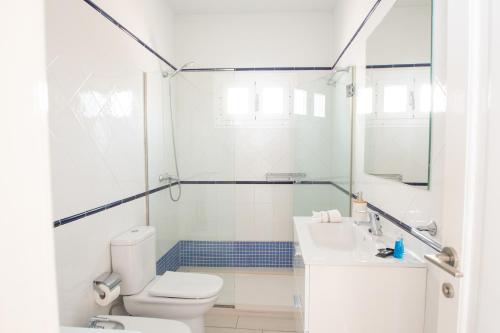 a white bathroom with a toilet and a sink at Blancazul Alto Brisa in Playa Blanca