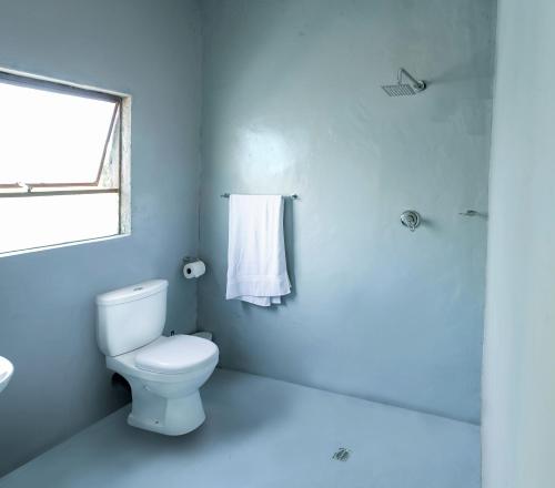 baño blanco con aseo y ventana en White Oak Place, en Katoen