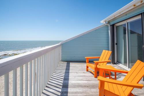 two orange chairs sitting on a deck near the beach at Oceanfront Condo with 3+ Pools - Ocean Dunes 2003 in Kure Beach