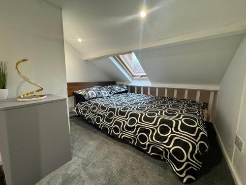 een slaapkamer met een bed met een zwart-wit dekbed bij Duplex Studio 3 minute drive from Luton airport in Luton