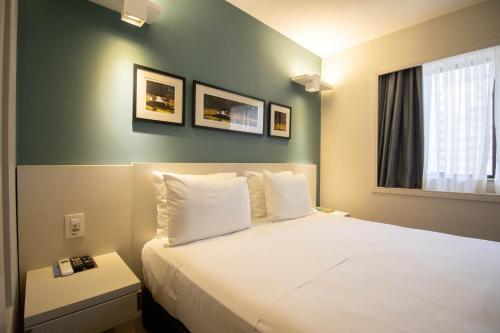 une chambre d'hôtel avec un lit avec des oreillers blancs dans l'établissement Charmoso e central, à Brasilia