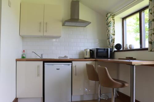 a kitchen with white cabinets and a counter and chairs at Malthouse Farm Cottage Studio in Dilhorne