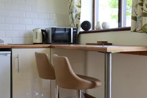 uma cozinha com um balcão com 2 cadeiras e um micro-ondas em Malthouse Farm Cottage Studio em Dilhorne