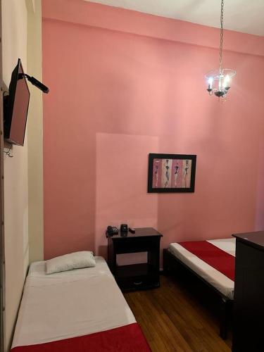 2 Betten in einem Zimmer mit einer rosa Wand in der Unterkunft Boutique del cafe in Manizales