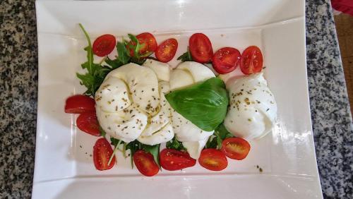 a white plate of food with tomatoes and cauliflower at Hôtel Saint Jacques in Thorigné-sur-Dué