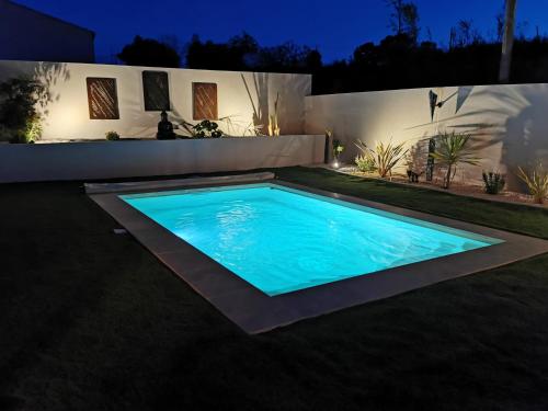 a swimming pool in a backyard at night at Villa moderne, piscine privée Cruzy in Cruzy