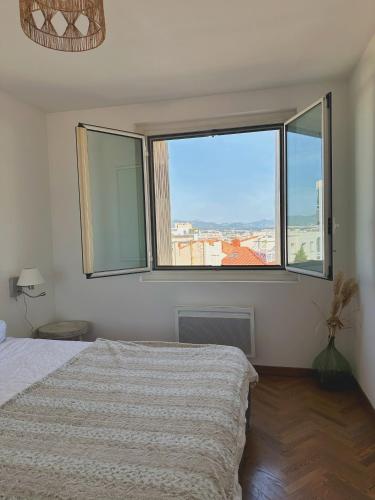 une chambre avec un lit et deux grandes fenêtres dans l'établissement Charmant T2 - vue imprenable sur Marseille, à Marseille